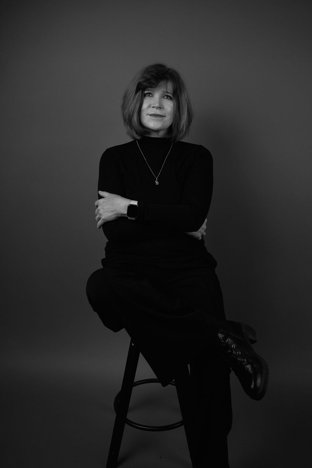 Frau in Schwarz auf einem Hocker im Studio