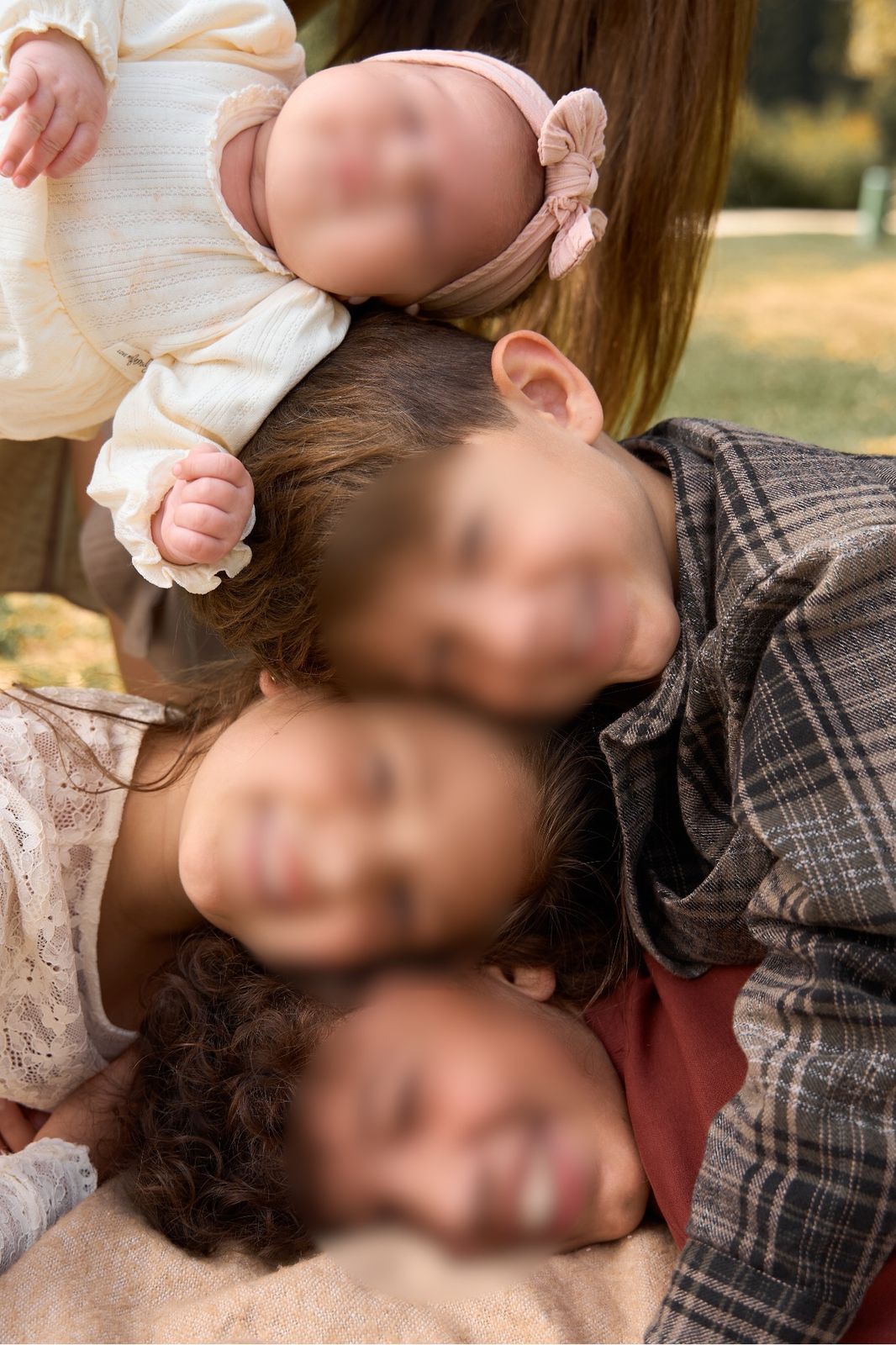 Kinder liegen Kopf an Kopf, ein Baby obenauf