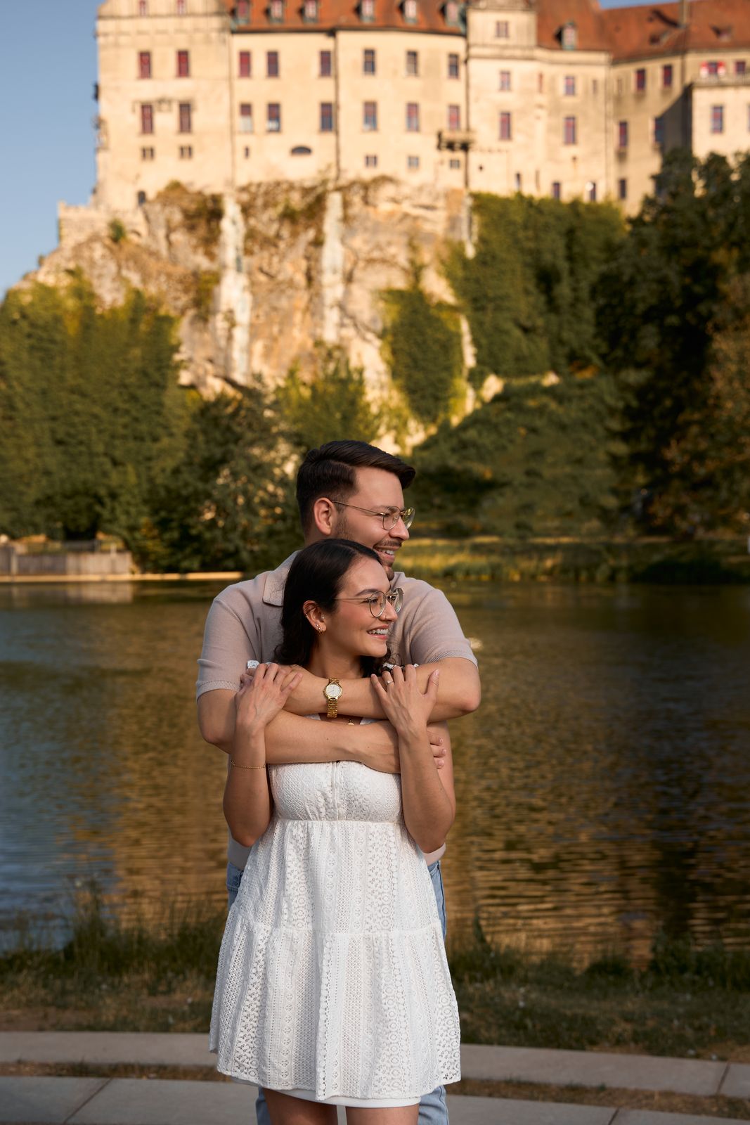Paar umarmt sich am Ufer vor einem Schloss