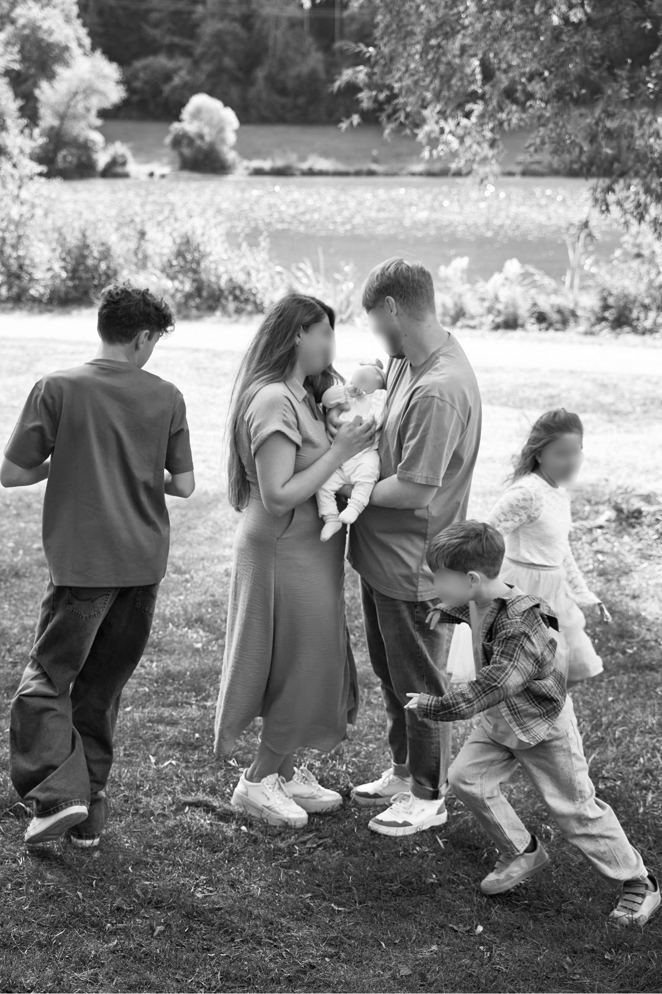 Familie mit Baby und Kindern auf einer Wiese, schwarzweiß